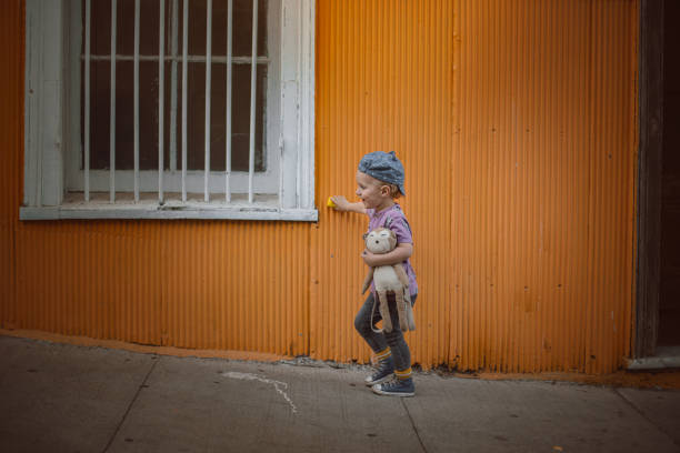 boy with toy car and teddy bear waling in a colorful street with car on the wall - valparaiso chile foto e immagini stock
