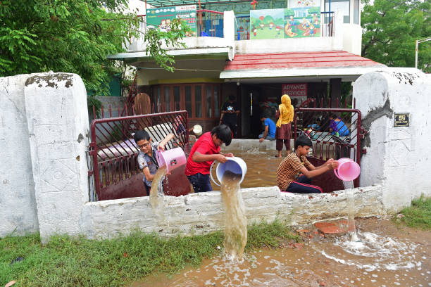 Boys pour out rain water from their partially submerged house after heavy rains in Ahmedabad on July 11, 2022.