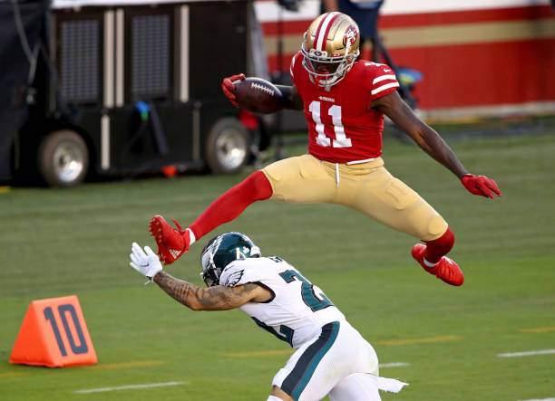 Brandon Aiyuk of the San Francisco 49ers leaps over Marcus Epps of the Philadelphia Eagles to score a touchdown against the Philadelphia Eagles...