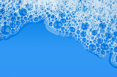 Bubble foam soap shampoo on blue water surface texture background top view