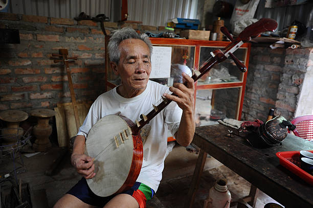 Bui Van Vuoc plays a dan nguyet instrument at his workshop in Vinh Bao on September 19 2015 in Hai Phong Vietnam 81yearsold Bui Van Vuoc of Bao Ha...