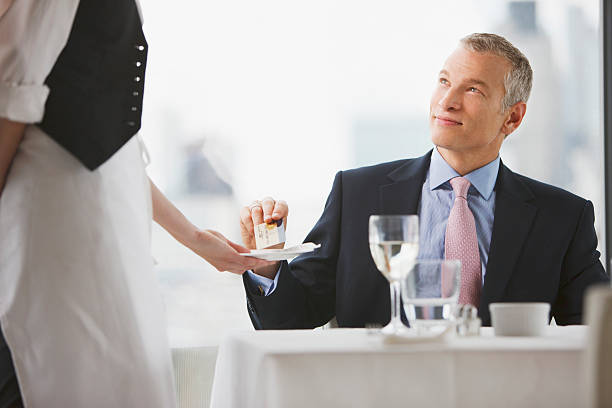 businessman handing waitress credit card in restaurant - man giving money stock pictures, royalty-free photos & images