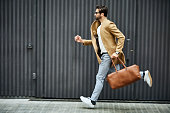 Businessman with bag running on sidewalk in city