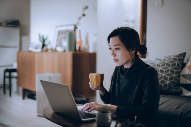busy concentrated young asian woman working from home, working on laptop till late in the evening at home. home office, overworked, deadline and lifestyle concept - contabilidade - fotografias e filmes do acervo