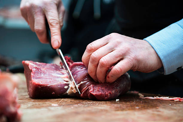 butcher preparing meat in butchers shop closeup picture