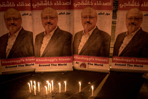 Candles are seen in front of posters of Jamal Khashoggi during a candle light vigil held to remember journalist Jamal Khashoggi outside the Saudi...