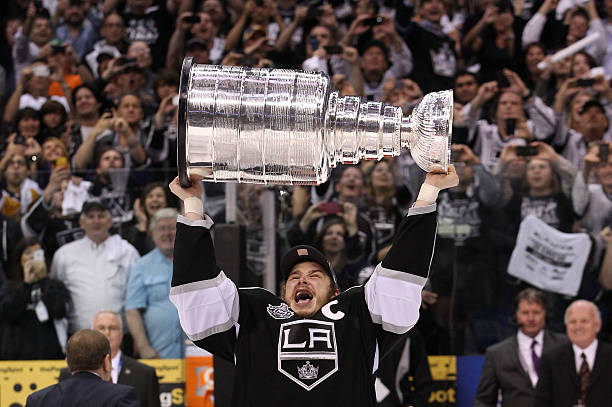 Captain Dustin Brown of the Los Angeles Kings holds up the Stanley Cup after the Kings defeat the New Jersey Devils 6-1 to win the Stanley Cup in...