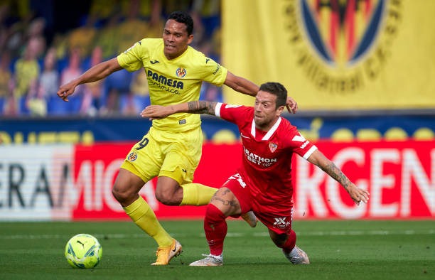 Carlos Bacca of Villarreal CF competes for the ball with Papu Gomez of Sevilla FC during the La Liga Santander match between Villarreal CF and...