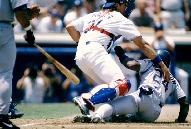 Catcher Mike Piazza of the Los Angeles Dodgers is slid into by Rickey Henderson of the San Diego Padres during an MLB game circa 1996 at Dodger...