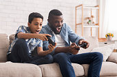 Cheerful Black Father And Son Competing In Video Games At Home