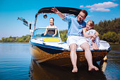 Cheerful father telling daughter stories while sailing boat