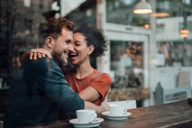 cheerful woman sitting with arm around on man at cafe - couple cafe stock pictures, royalty-free photos & images