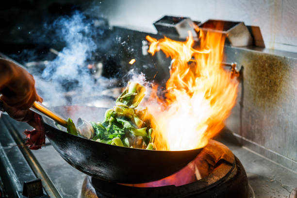 chef in restaurant kitchen at stove with high burning flames picture