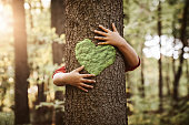 Child hugging tree with heart shape on it