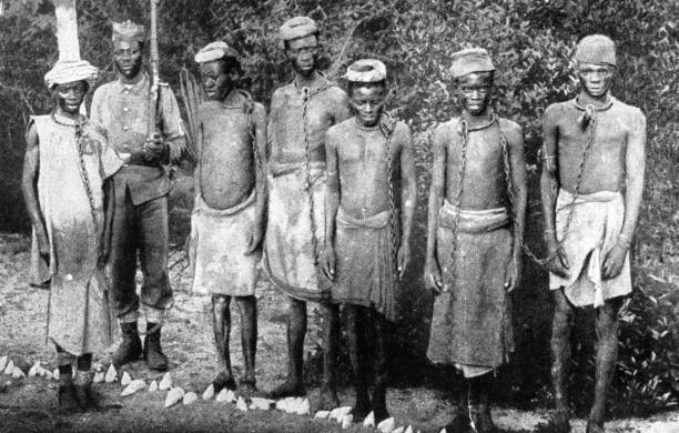 Slaves in chains, guarded by a native Askari, or soldier.