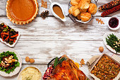 Classic Thanksgiving turkey dinner. Top down view frame on a rustic white wood background.