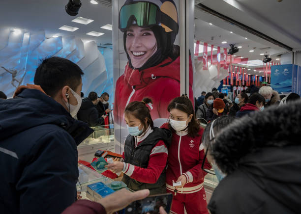 Clerks process payments from customers under a photo of American born freestyle skiing gold medallist Eileen Gu who competes for China at the...