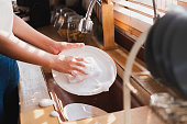 Close up maid housewife washing cleaning dishes in kitchen