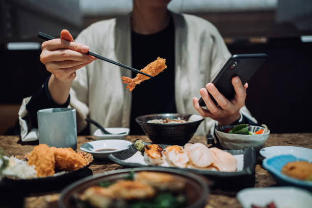 close up midsection of asian woman using smartphone while eating picture
