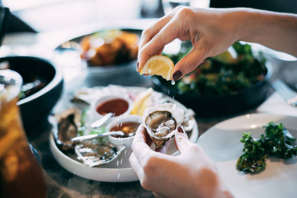 close up of a womans hand squeezing lemon juice on to a fresh oyster picture