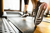 Close up of unrecognizable athlete running on a treadmill in a gym.