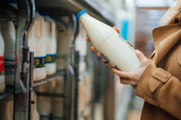 close up shot of woman holding a bottle of organic fresh milk in supermarket - oat milk ストックフォトと画像
