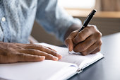Close up view of african left-handed businessman writing in notebook