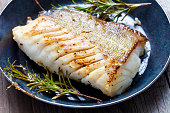 Close-up of a cod fillet with rosemary on a plate