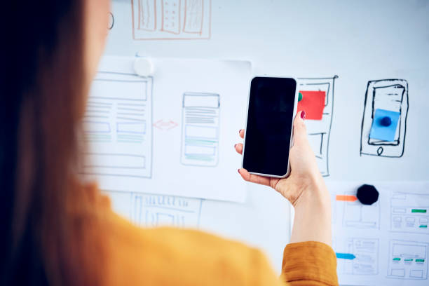 close-up of businesswoman holding smartphone at whiteboard in office - web designer stock pictures, royalty-free photos & images