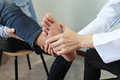 Closeup of Man feeling pain in her foot and doctor the traumatologist examines or treatment on white background, Healthy concept