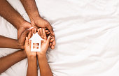 Closeup of paper house in hands of african american family