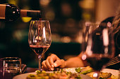 Close-up of sommelier serving red wine at fine dining restaurant