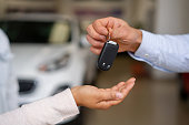 Close-up on a salesman giving the keys to their new car to a couple at the dealership