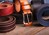 Collection of leather belts on a wooden table