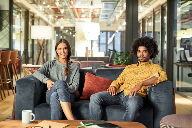 confident coworkers sitting on sofa in office - man and women stock pictures, royalty-free photos & images