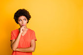 Copyspace photo of contemplating watching looking staring girlfriend wearing orange t-shirt touching her chin pondering over something to choose isolated over yellow vivid color background