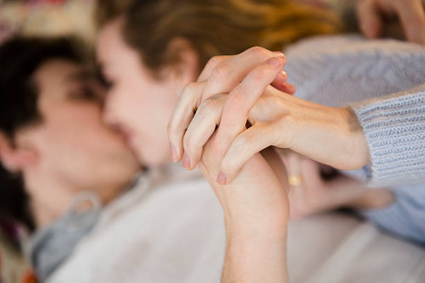 couple holding hands while kissing - love stock pictures, royalty-free photos & images