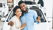 Couple Showing New Car Key Smiling In Dealership Showroom, Panorama