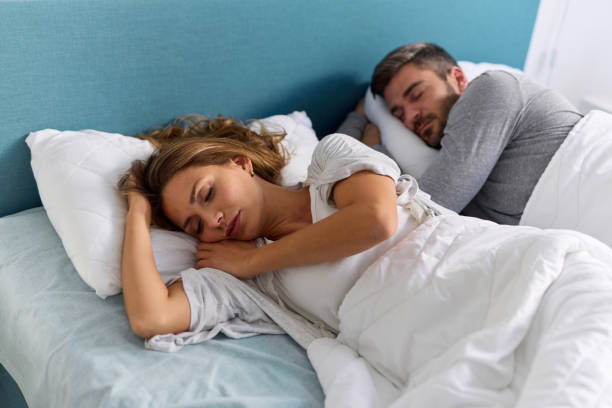 couple sleeping peacefully in their bed at home - couples romance good night stock pictures, royalty-free photos & images