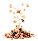 Crispy granola with raisins and banana falling on a heap on a white background. Isolated