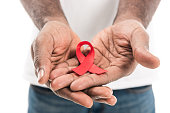 cropped shot of african american man holding aids awareness red ribbon isolated on white
