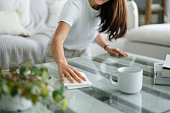 Cropped shot of young Asian woman tidying up the living room and wiping the coffee table surface with a cloth
