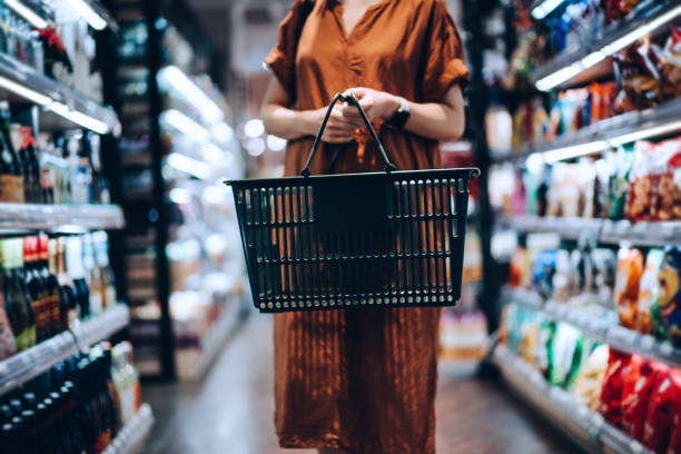 cropped shot of young woman carrying a shopping basket standing along picture