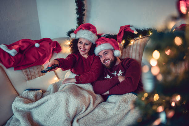 cute couple enjoying christmas with tv and movie under the blankets - couple stock pictures, royalty-free photos & images
