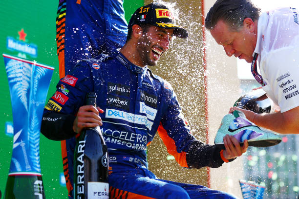 Daniel Ricciardo of Australia and McLaren celebrates with a shoey on the podium as McLaren CEO Zak Brown pours the sparkling wine following his...