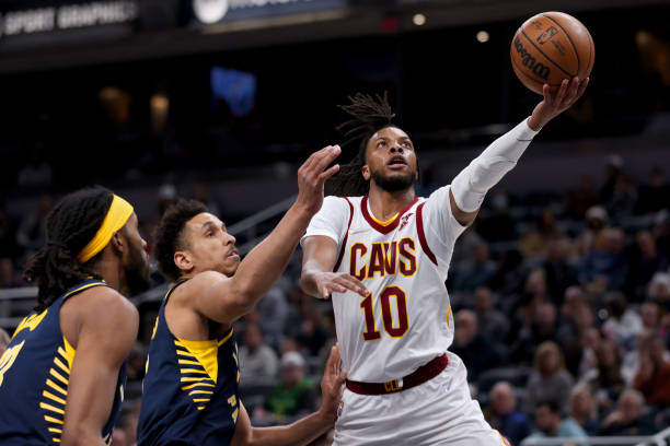 Darius Garland of the Cleveland Cavaliers attempts a layup while being guarded by Isaiah Jackson and Malcolm Brogdon of the Indiana Pacers in the...