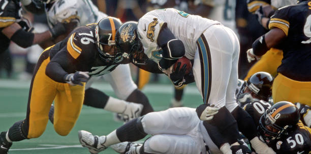 Defensive lineman Kevin Henry and linebacker Earl Holmes of the Pittsburgh Steelers tackle running back Fred Taylor of the Jacksonville Jaguars...