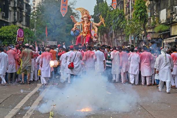 Devotees burn firecrackers as they carry an idol of the elephant-headed Hindu deity Ganesha during an immersion procession to the Arabian sea on the...