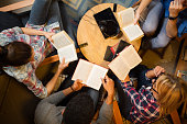 Diverse group of friends discussing a book in library.