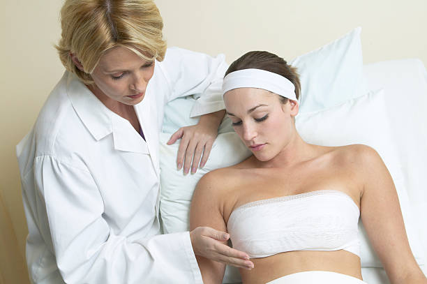 doctor examining bandaged woman - mamoplastia - fotografias e filmes do acervo